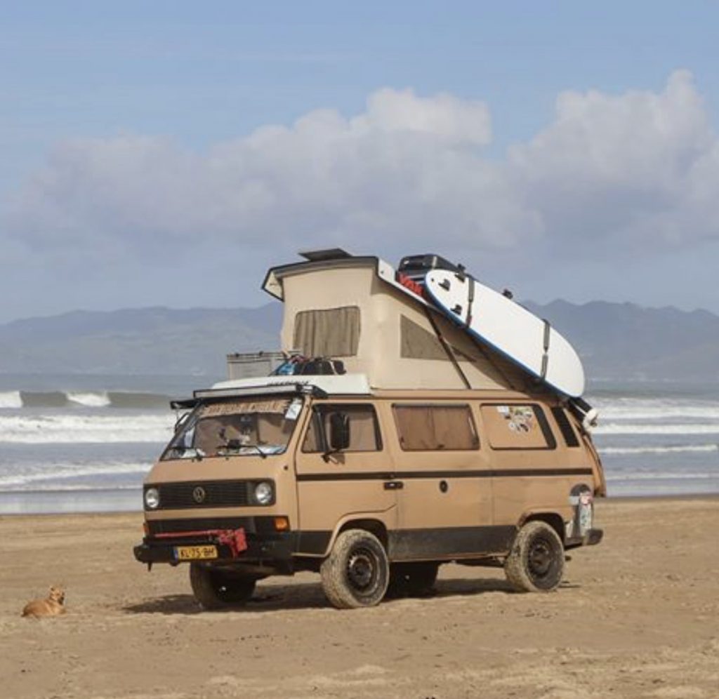Pop up camper - beige VW west’s pop up on beach with surf board 