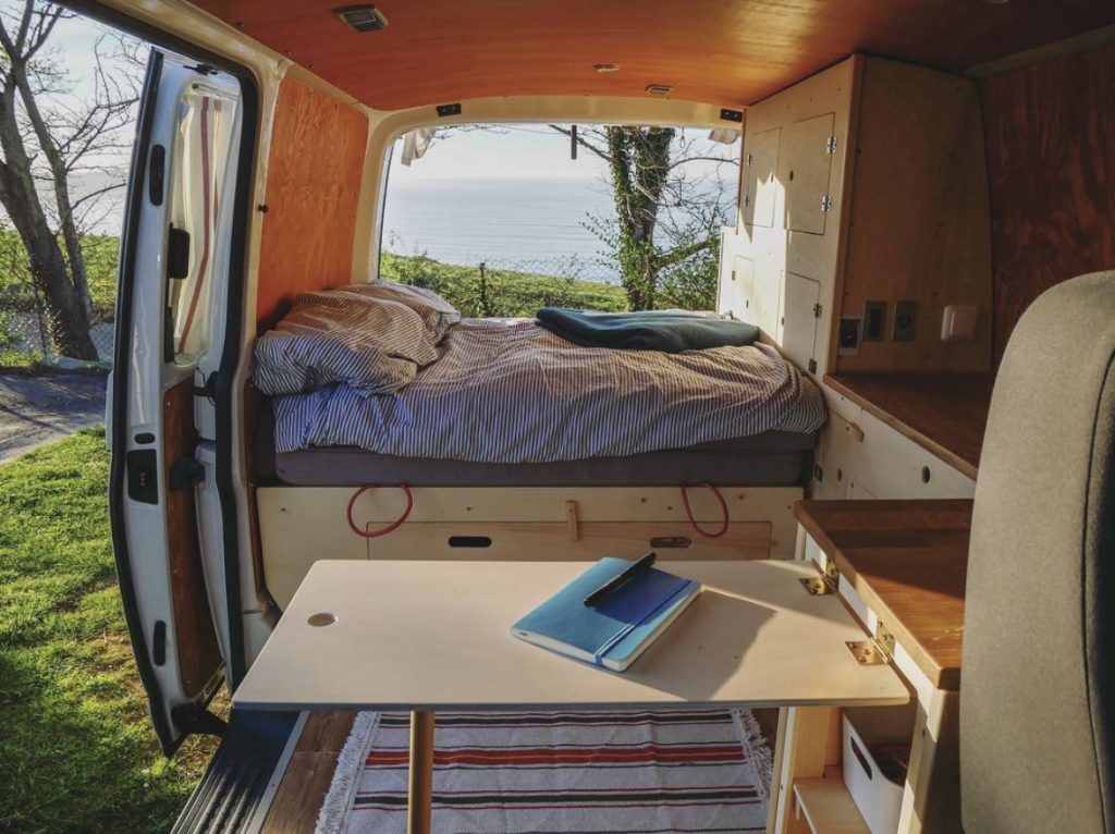 Stealth campers - van interior with table up and bed made 