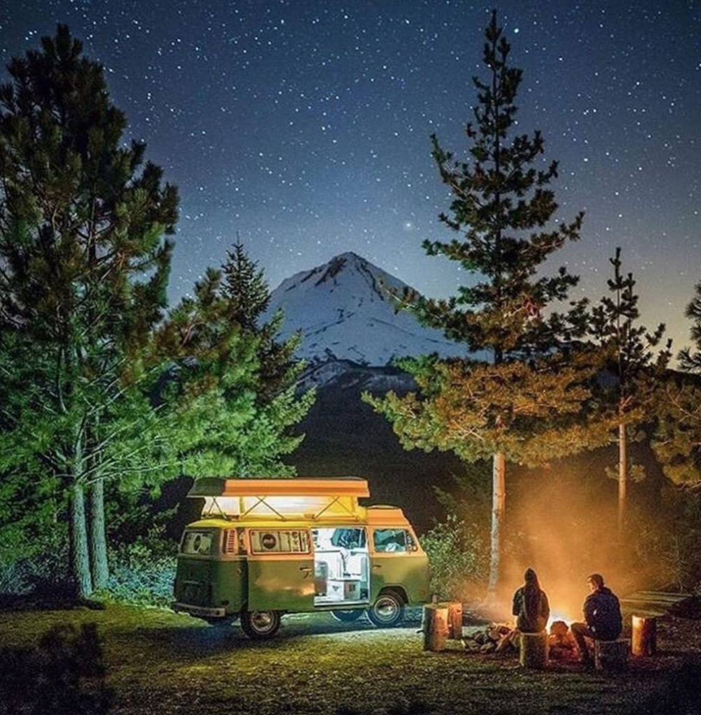 VW bus under the stars next to a camp fire