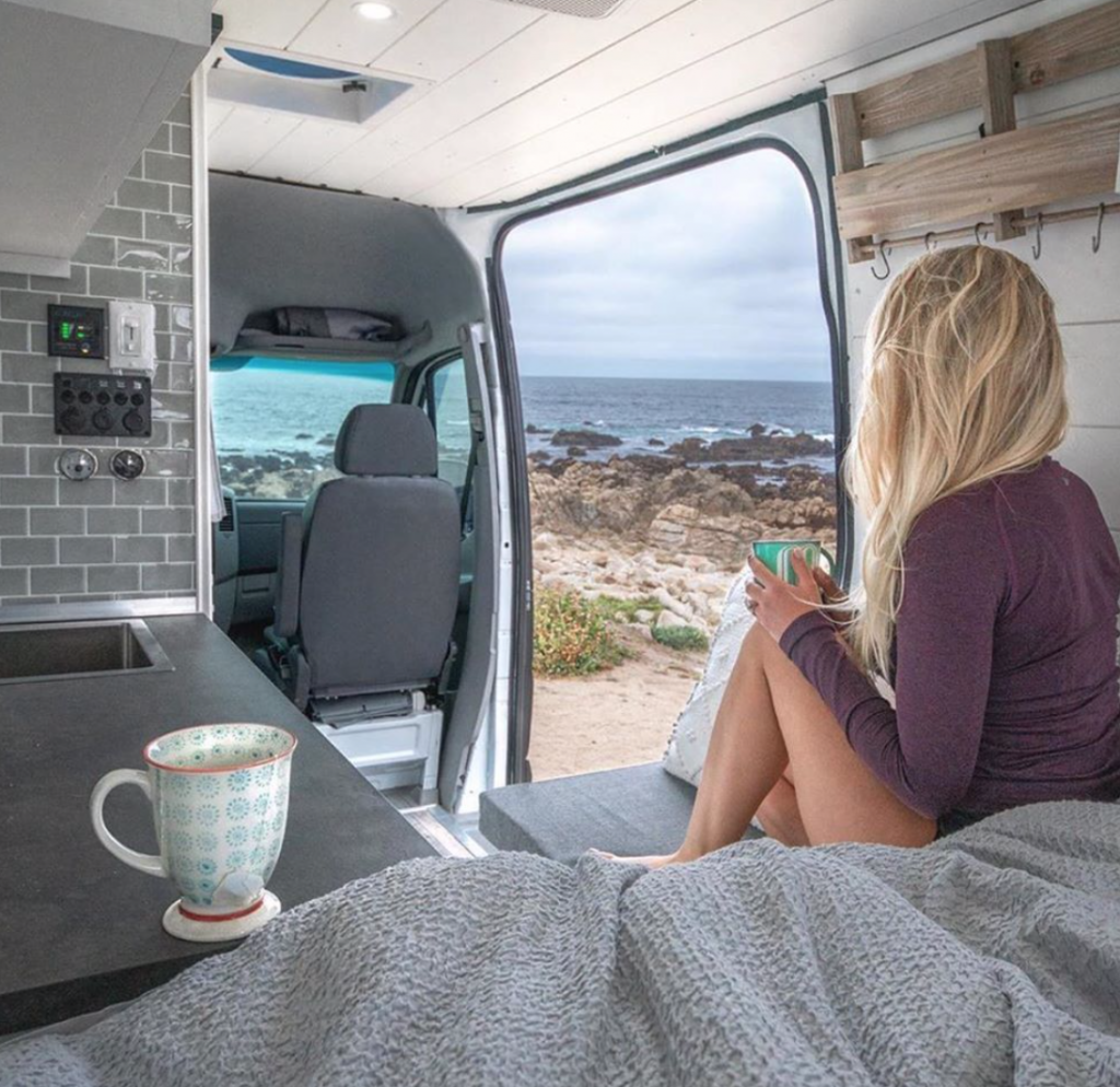 Girl looking out at the sea in her Off Grid Camper