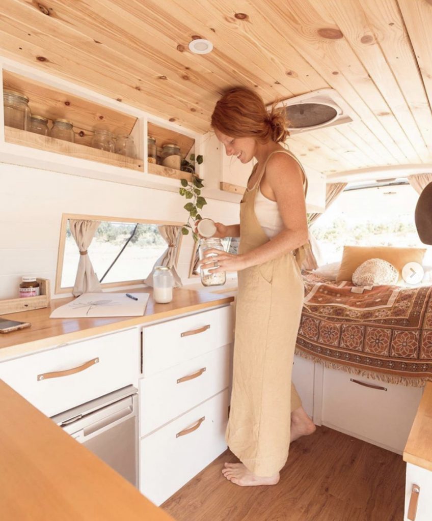Woman making a drink in her camper van kitchen. 