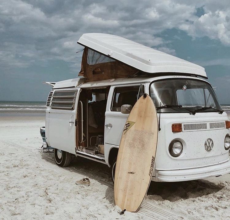 White VW pop top parked on beach with surf board 