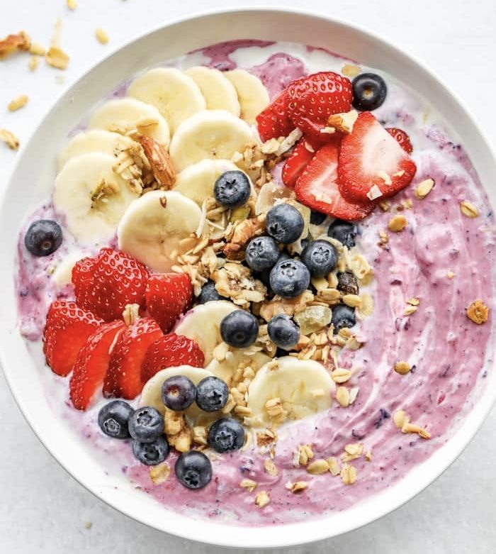 campervan recipes: pink smootie bowl with banana, berries and granola on top 