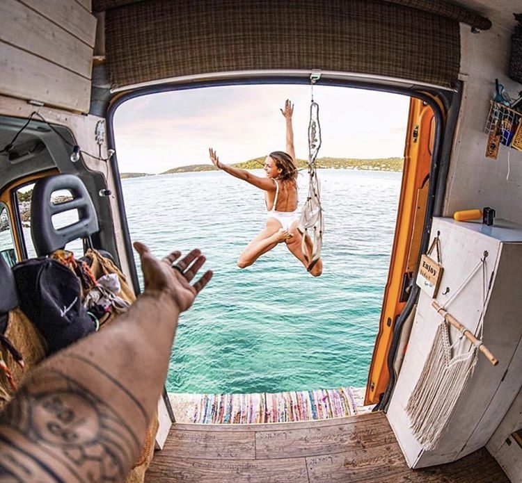 camper life - woman jumping oiut of van and into water 