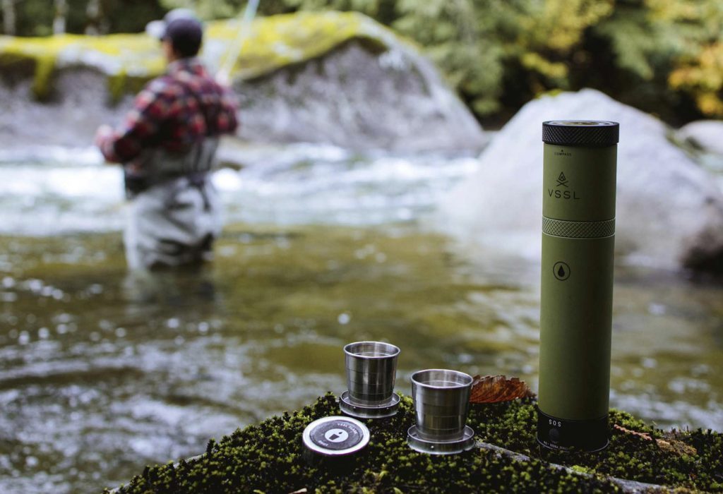 VSSL Flask with cups out on rocks by a river 
