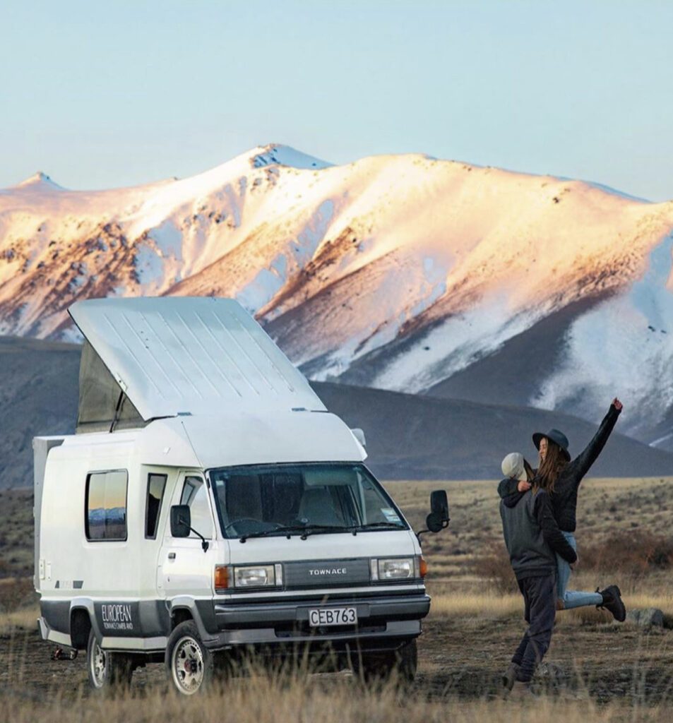 Van Camping - pop top van in front of mountains with couple next to it 