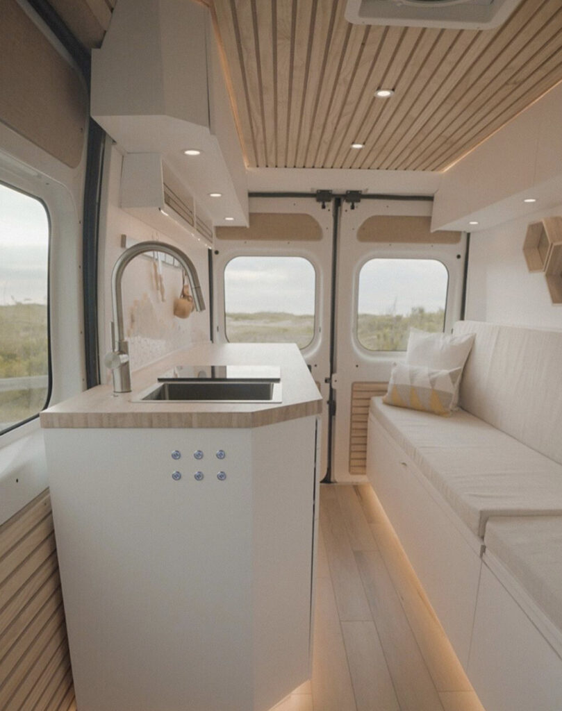 White interior of camper with kitchen and seat 