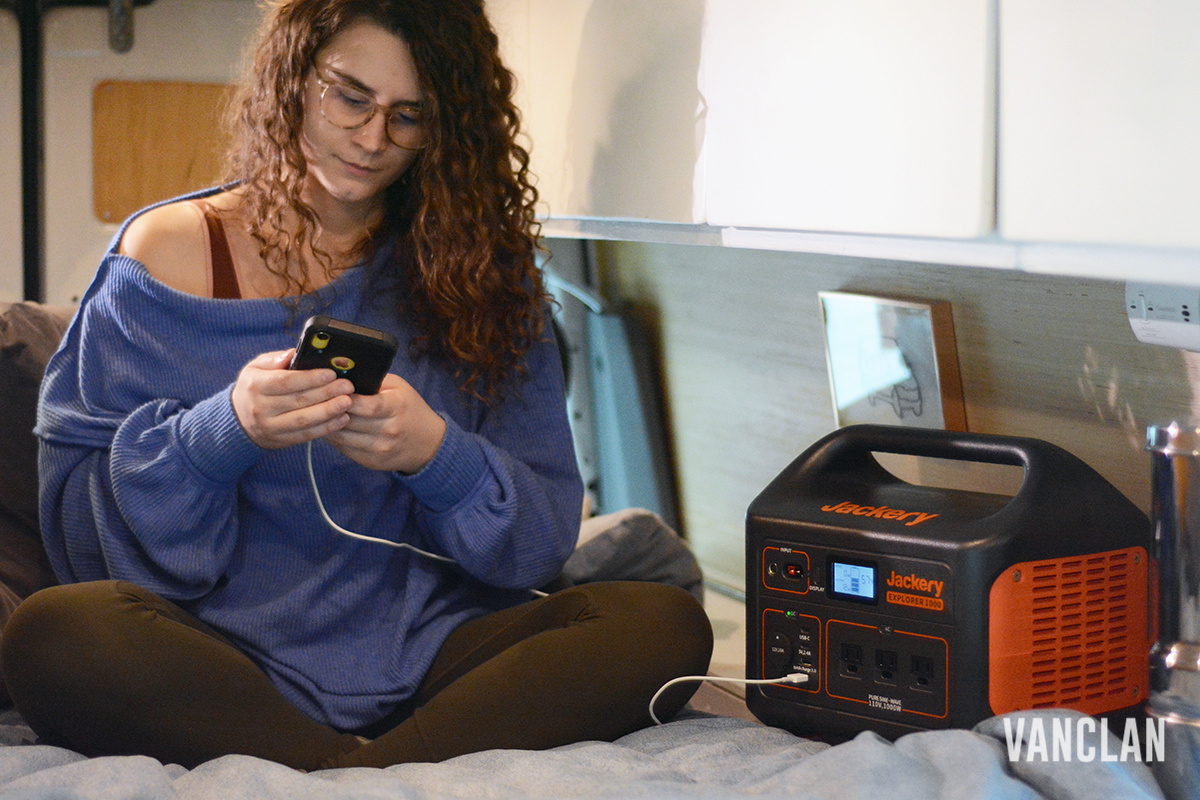 Jackery Explorer 1000 charging a phone with woman sitting on bed